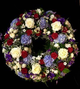 Trauerkranz mit blauen Hortensien, weißen und roten Rosen