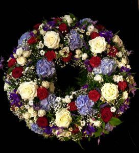 Trauerkranz mit blauen Hortensien, weißen und roten Rosen